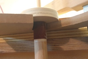 Der dritte Schleifblock aus Rundholz an der Stelle, wo der obere Cutout auf das Griffbrett trift; das flache runde Stück Sperrholz liegt auf der Oberfläche der schablone, das sandpapierbewehrte Stück Rundholz hängt senkrecht nach unten